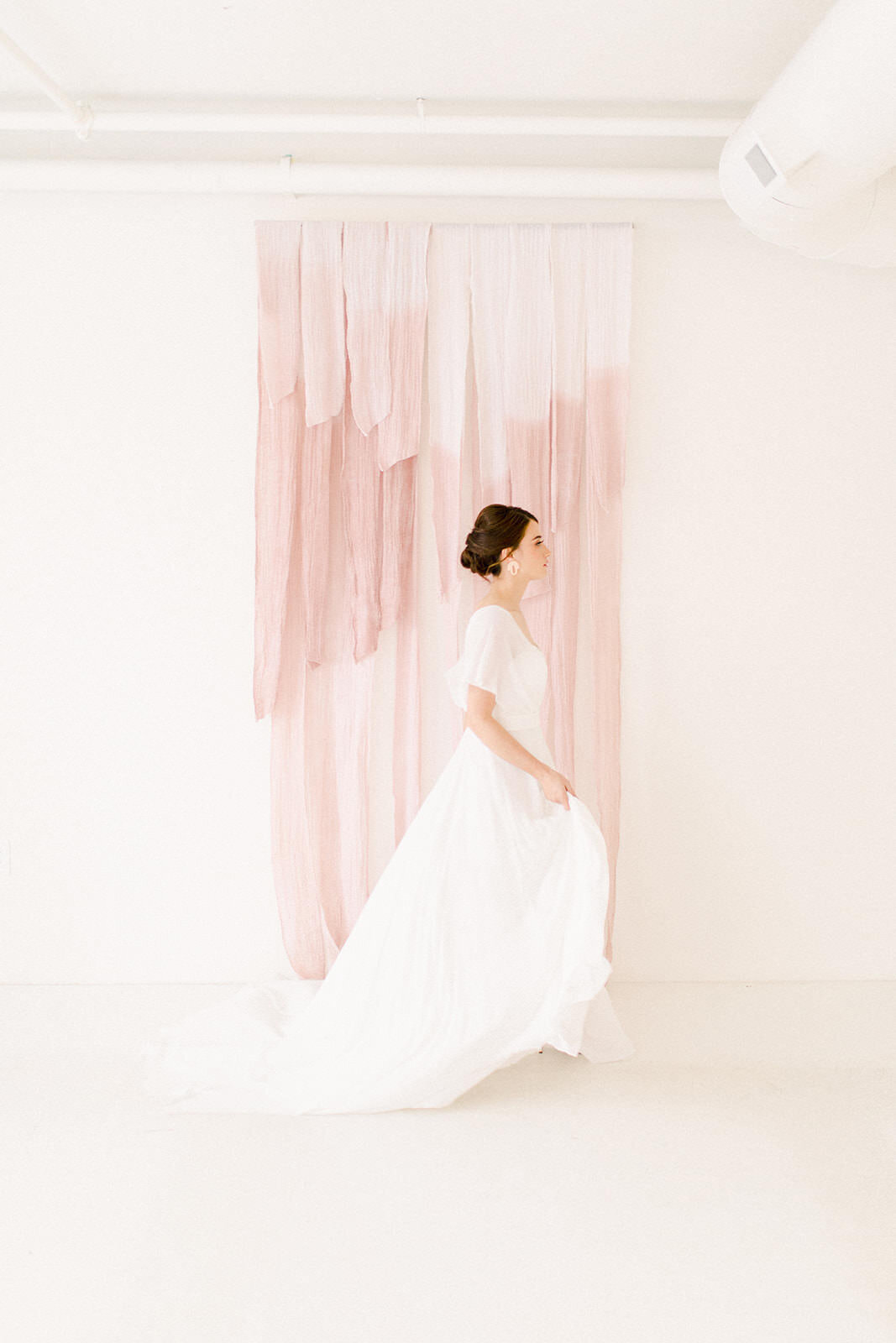 Bride walking in front of pink backdrop