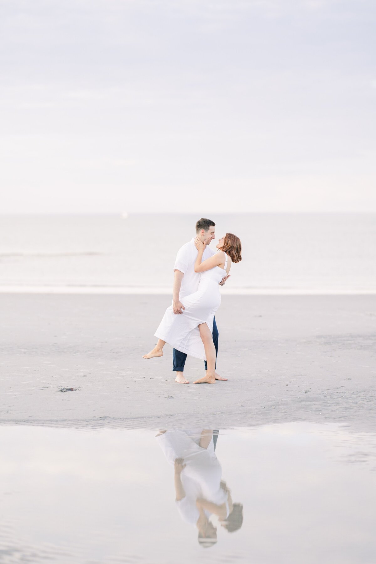 A couple sharing a dance at Wingaersheek Beach representing a Boston engagement photographer's portfolio.