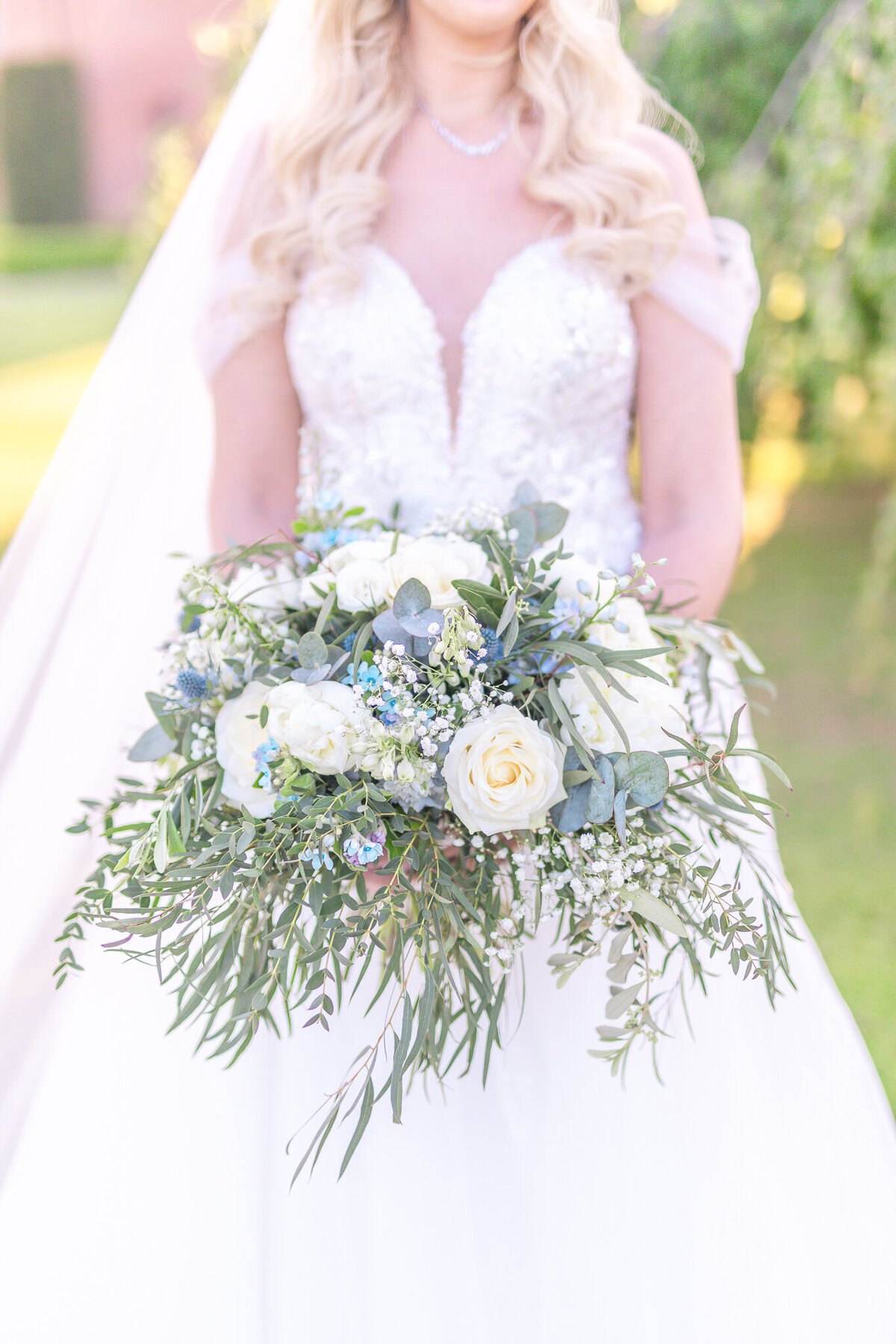 Bride holding white rose and blue flower bouquet