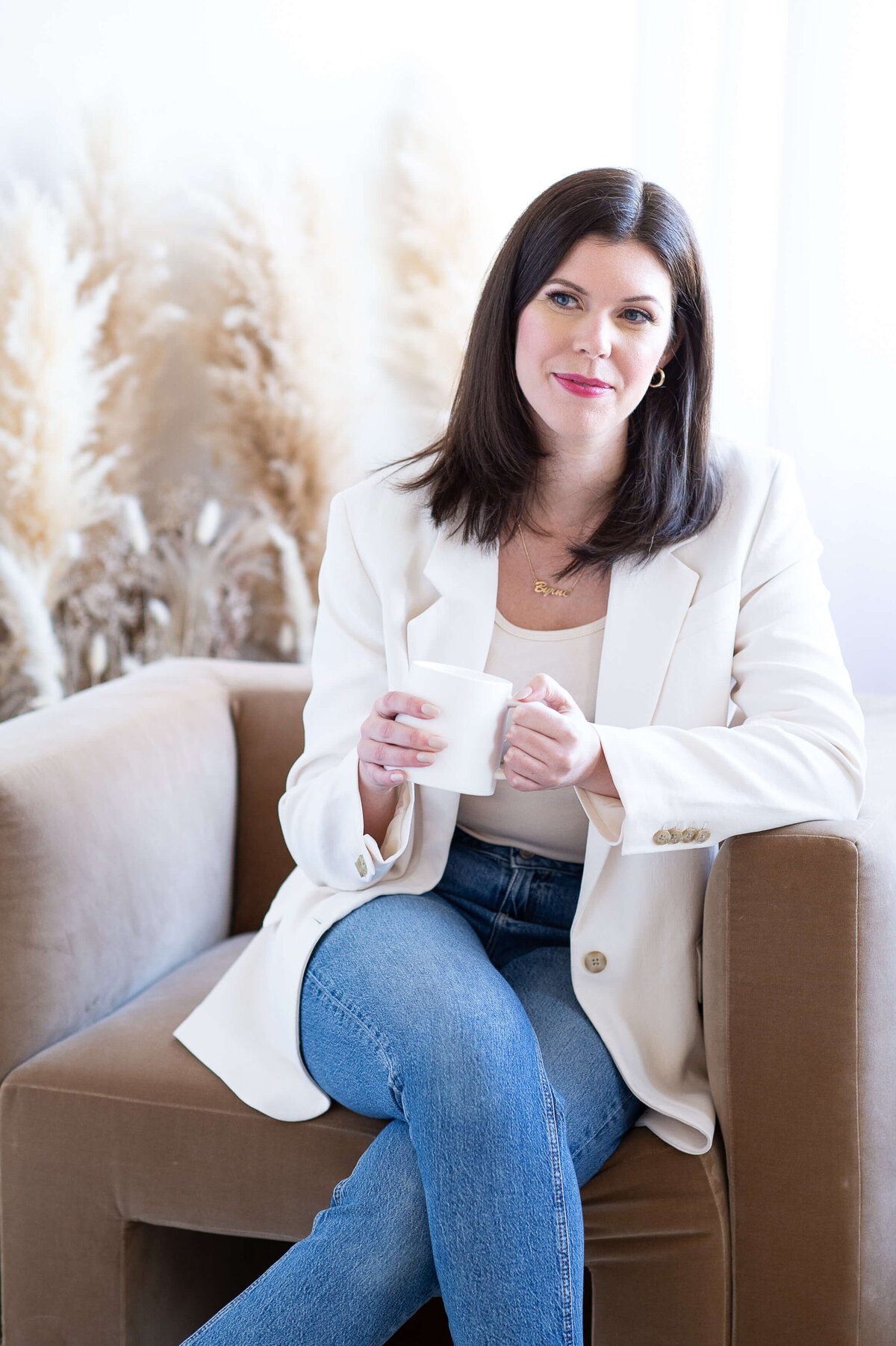Ottawa branding photography of a woman sitting in a chair holding a coffee cup looking off in the distance.  Captured by JEMMAN Photography