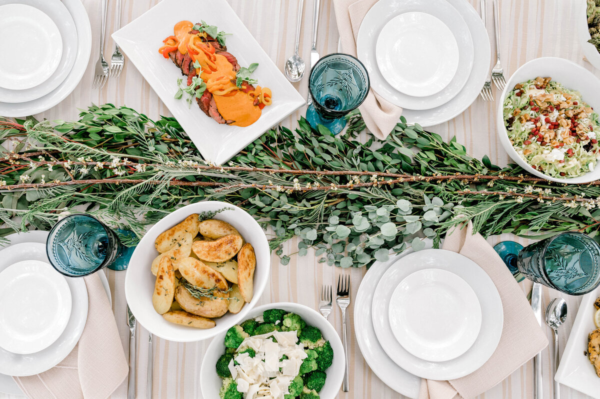 overhead image of a family style catered table at Willowbrook wedding venue with broccoli, roasted fingerling potatoes, beef tenderloin and shaved brussel sprouts