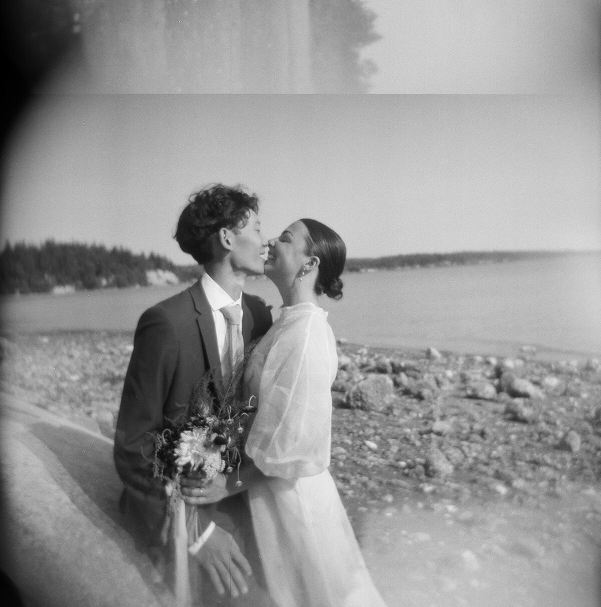 black and white holga image of couple kissing on the beach on their wedding day