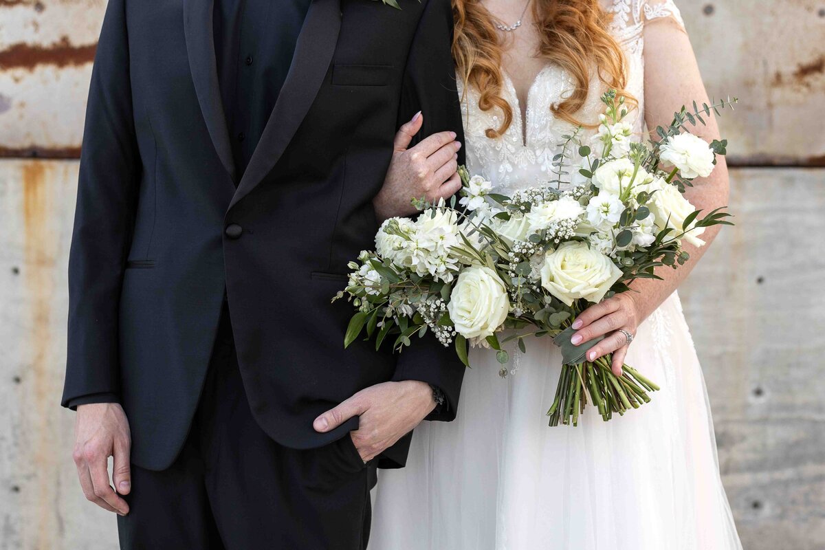 Bride holding groom's arm and her wedding bouquet