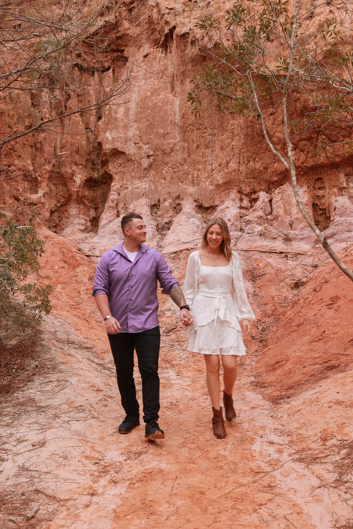 man and woman holding hands while walking in Providence Canyon State Park close to Columbus Georgia by Columbus Georgia engagement photographer Amanda Richardson Photography