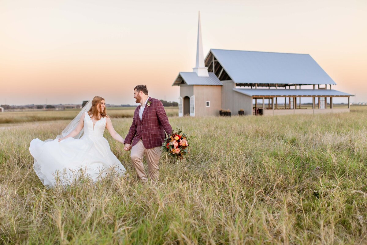 bride and groom skip through tall grass at sunset from chapel at Allen Farmhaus in New Braunfels Texas