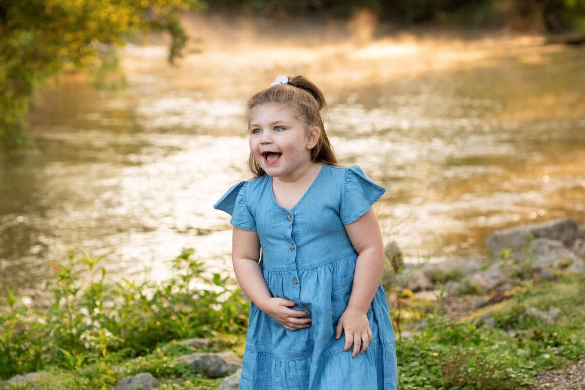 happy preschooler laughs near the river at Waterworks Park