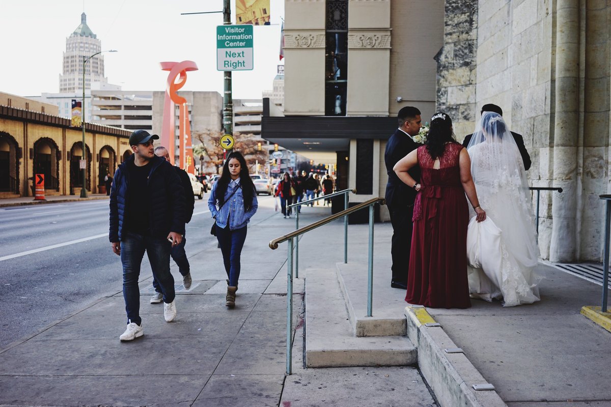 San Antonio Street photography of bride outside church and pedestrians looking at her