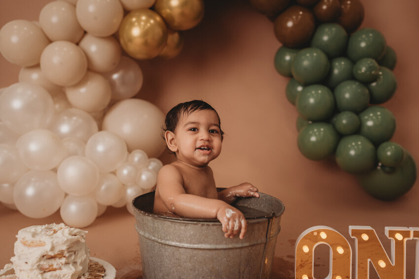 Cake smash milestone session with Atlanta, Georgia cake smash photographer. Milestone photography session with earthy tones, balloon garland and sweet baby boy eating cake for his first birthday.