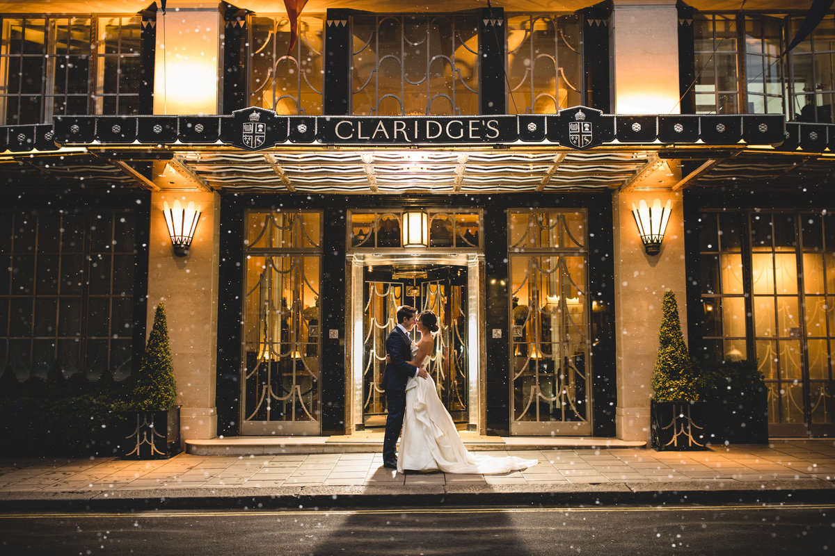 bride and groom on their wedding day in front of claridges in the snow