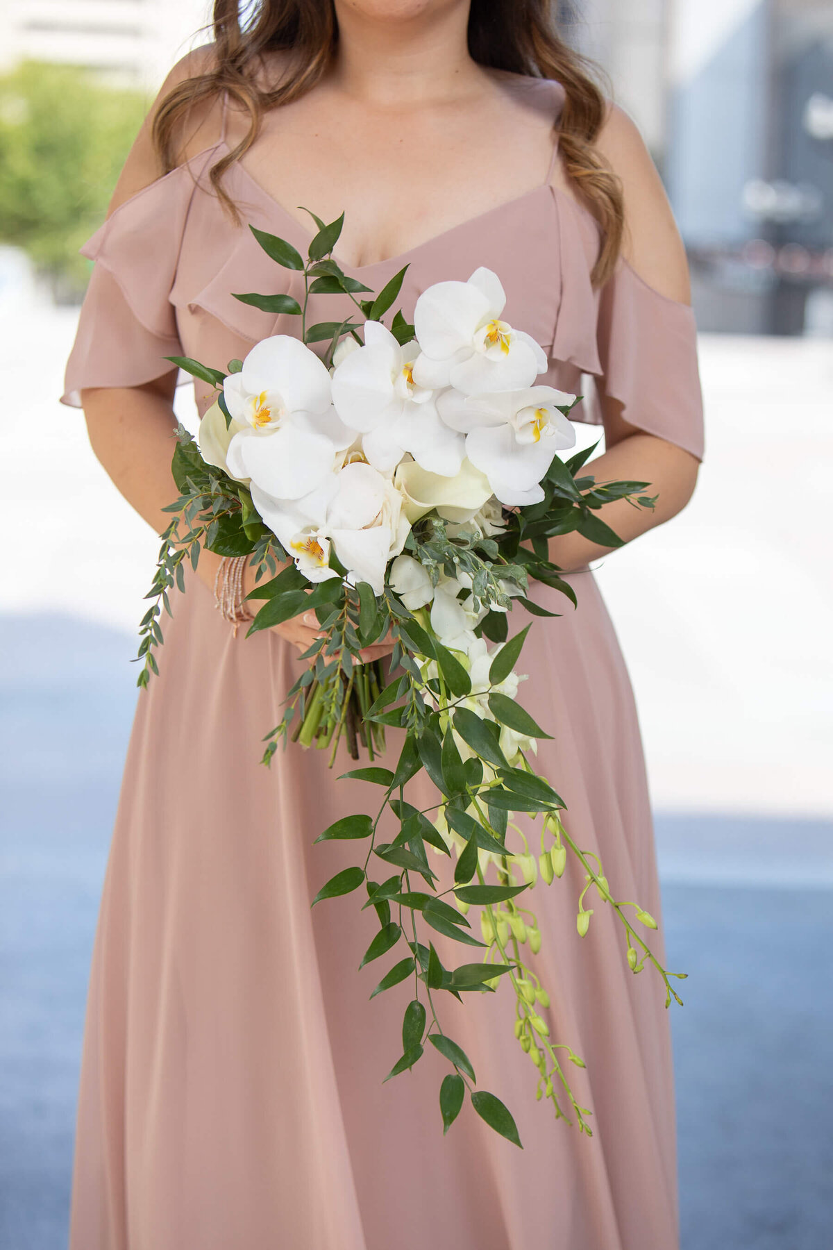 Bridesmaid in taupe blush silk dress with white orchid bouqet