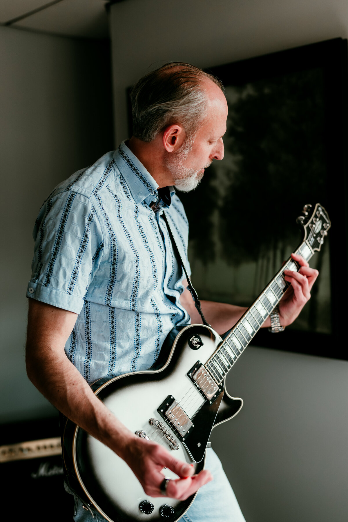 Authentic dating portrait of a man in his 50s playing guitar in his living room, highlighting creativity and soulful hobbies