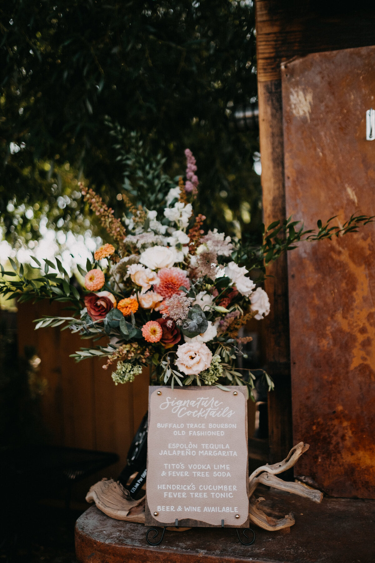 Leather bar sign with handpainted calligraphy next to florals