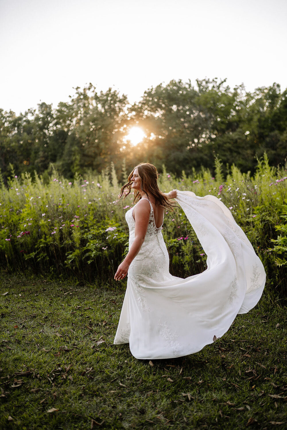 Bride twirling in gown with sunset backdrop in a field