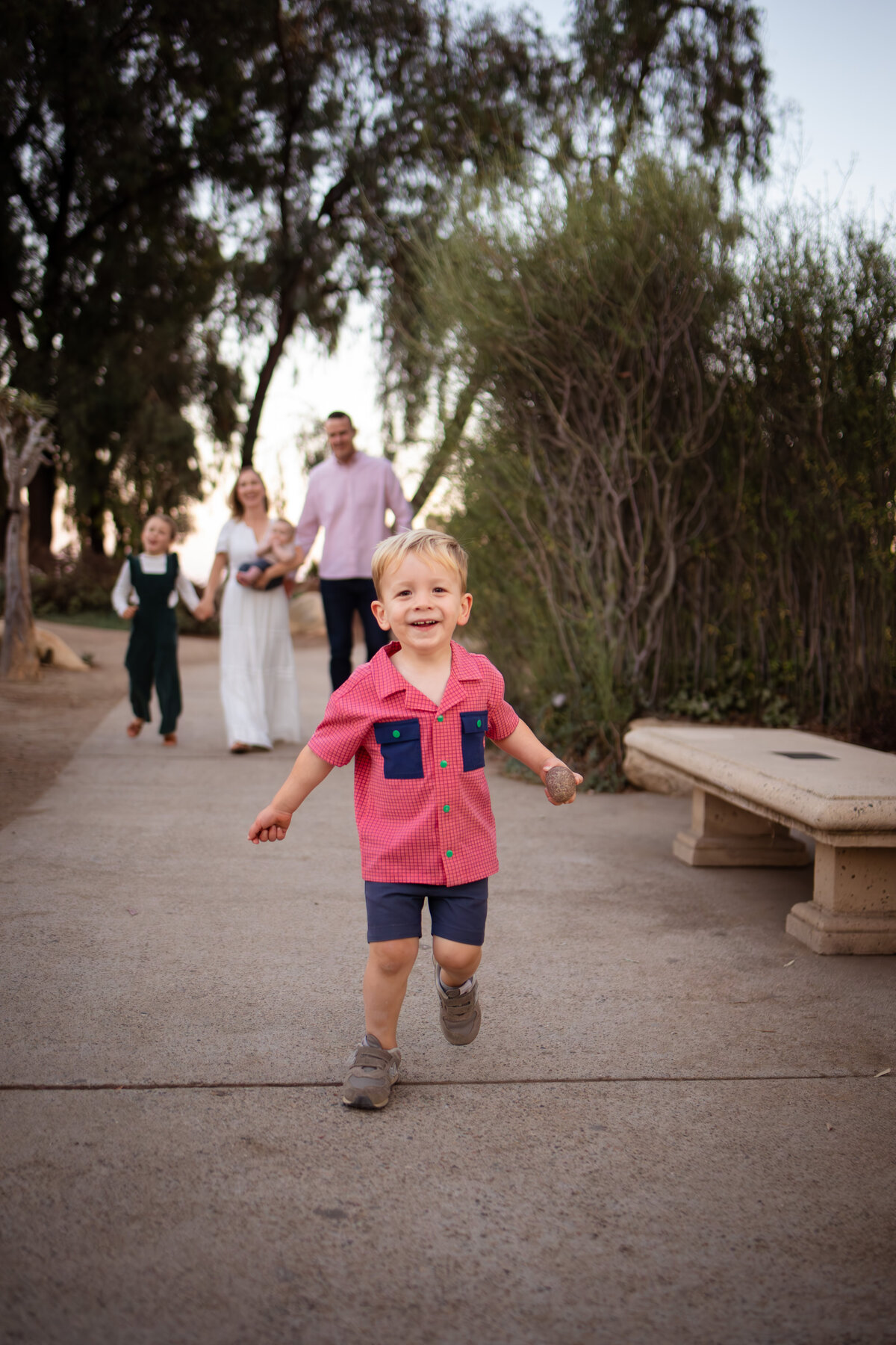 Little boy running towards the camera with family in the background