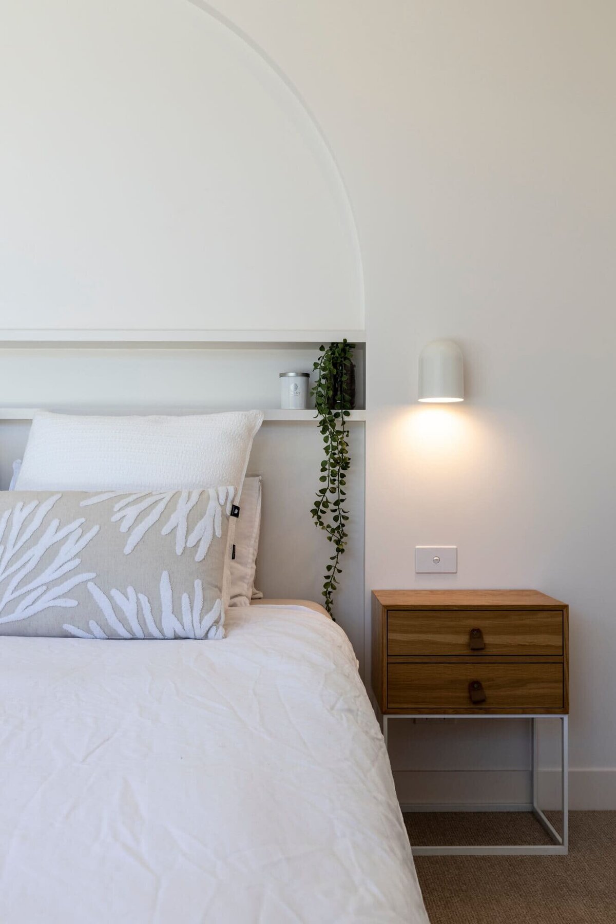 Half of a queen bed with beautiful grey sheets and a bed side lamp on