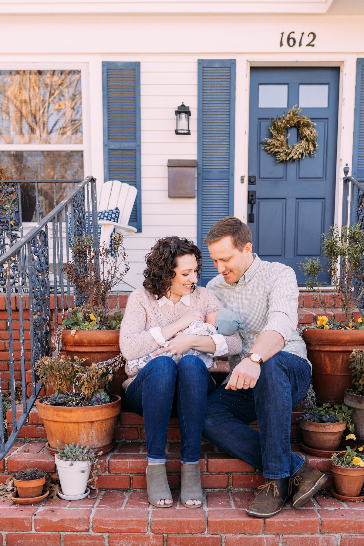 parents hold infant boy on porch