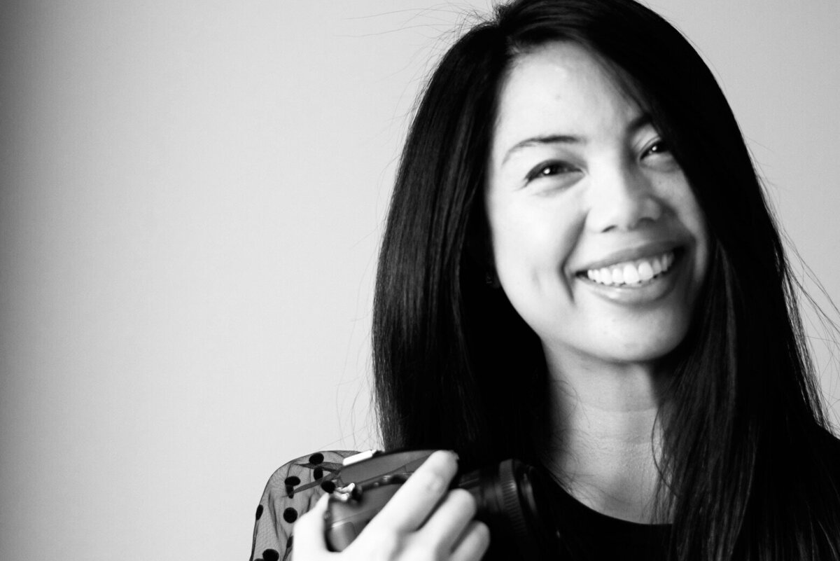 Wedding and Portrait Photographer's headshot in black and white smiling with camera
