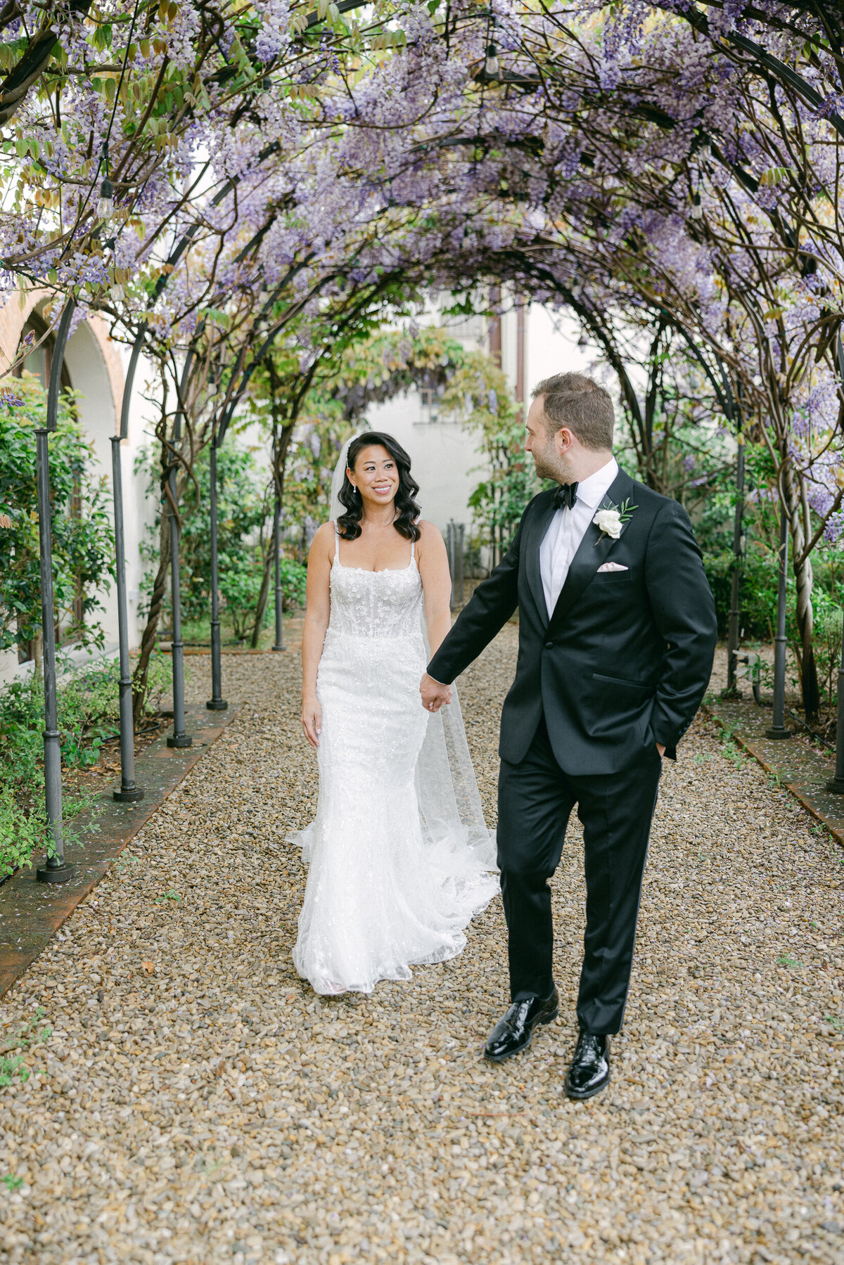 a bride and groom walking through a floral tunnel