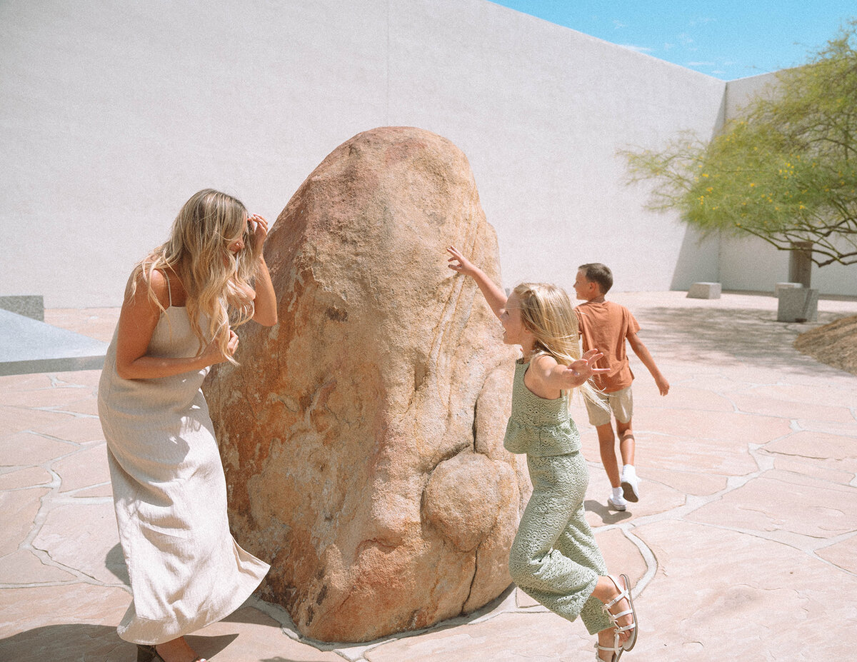 Orange County family photographer captures playful moments of kids climbing and laughing with their mom at Noguchi Garden in Irvine.