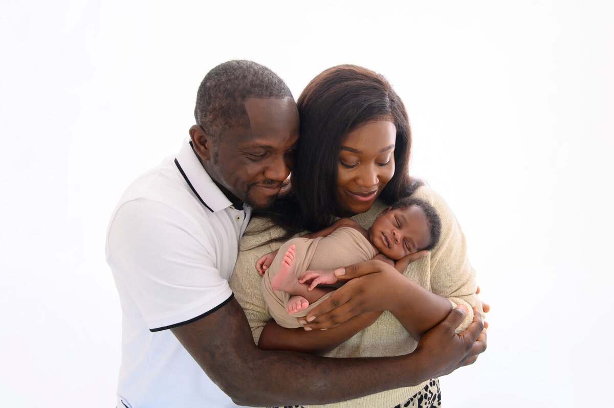 mom and dad cuddling holding newborn baby boy for his newborn photography session in Burlington, ON