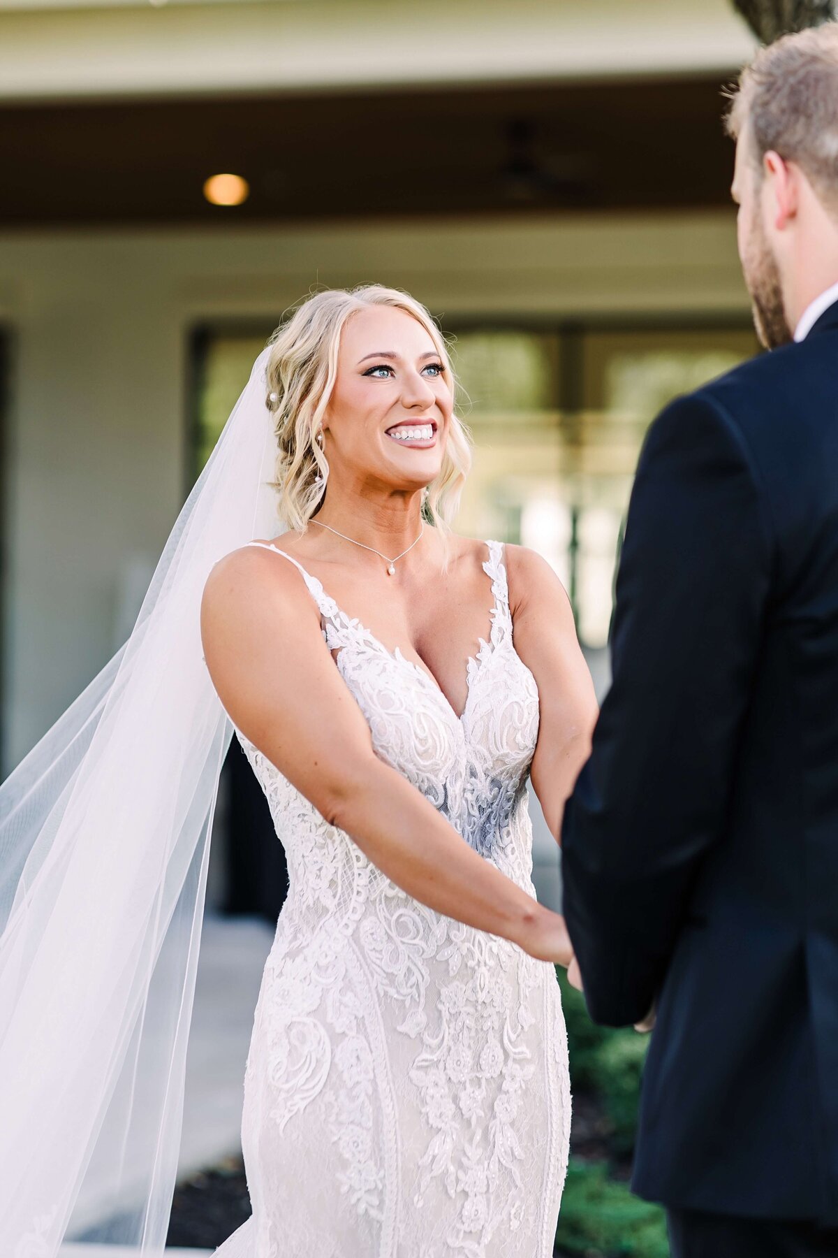 This bride glows with joy during a first look moment, styled with a romantic updo and flawless bridal makeup by Mistique Makeup. Her lace wedding dress and natural glam look are perfect for any bride searching for wedding hair and makeup near me or bridal hair and makeup in San Antonio, Dallas,  or Austin. Ideal inspiration for wedding day beauty.
