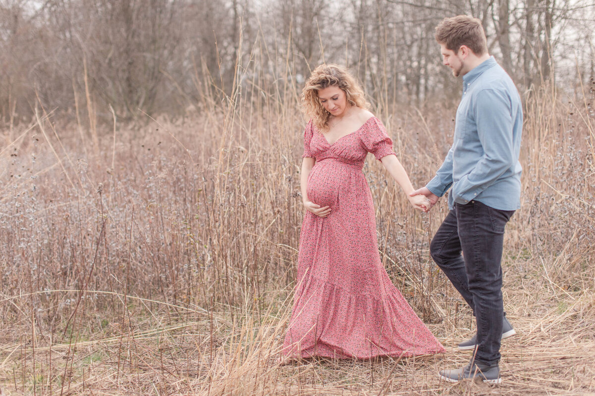 French Park Cincinnati Maternity Session Mom and Dad walking in a beautiful field