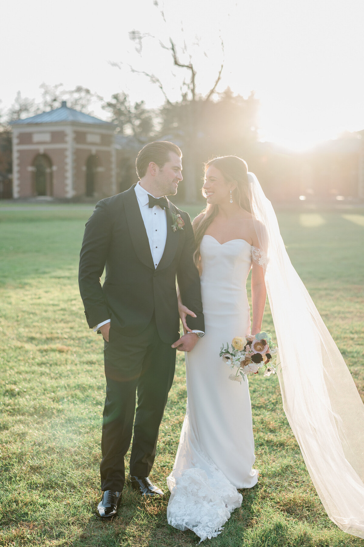 Bride and groom hold hands and walk during golden hour 