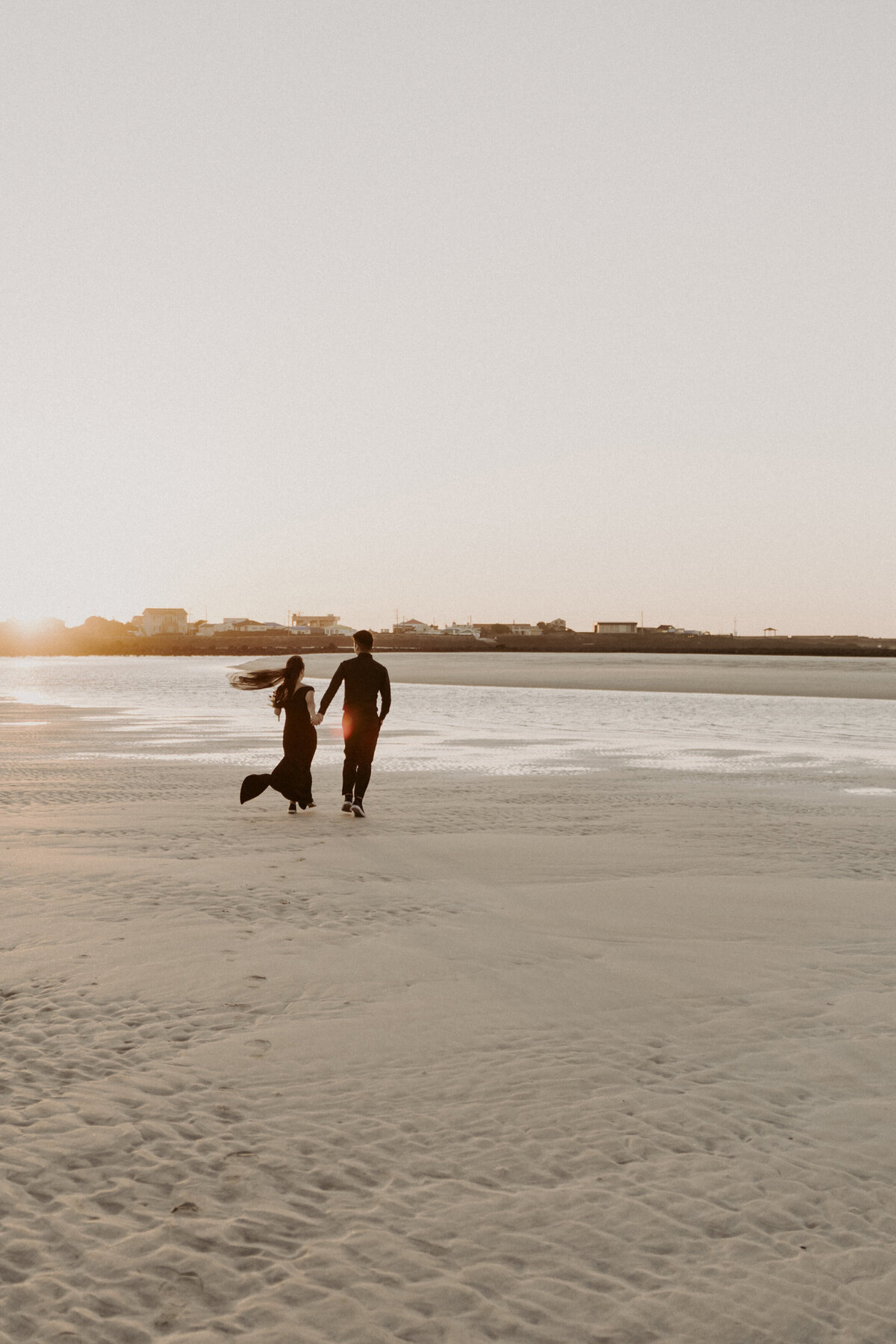 the couple running together while holding hands in one of the beach of Jeju Island