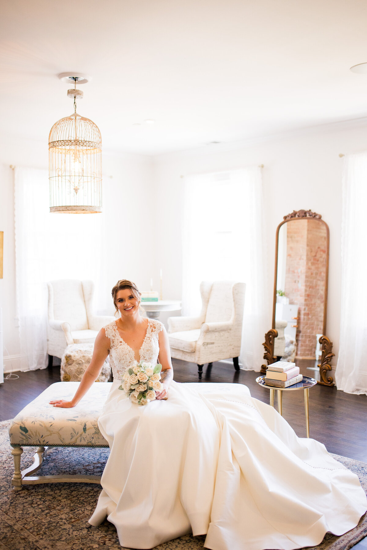 A wide angle shot of a bride smiling at the camera in an elegant getting ready space.