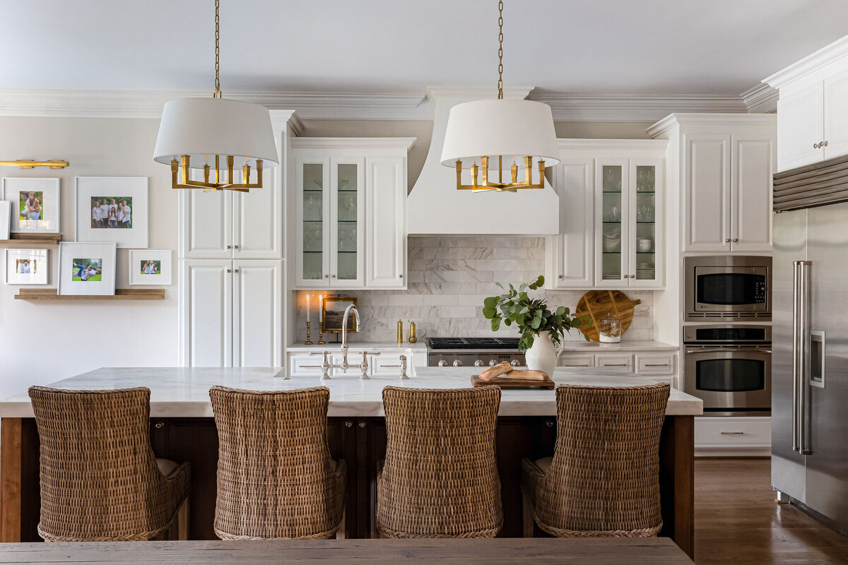 Traditional kitchen with white cabinetry, marble tile backsplash, and woven bar chairs.