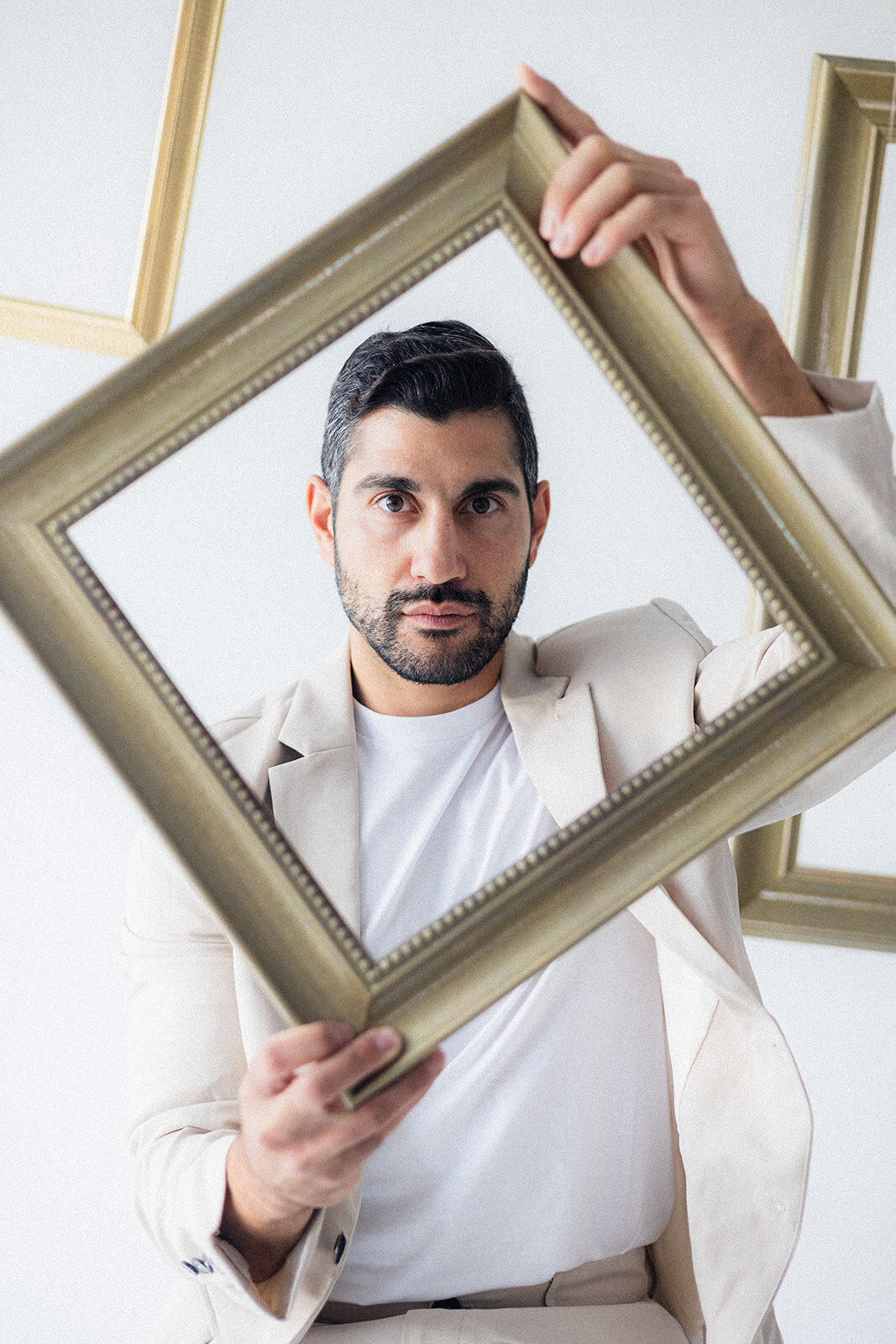 A man sits on a stool surrounded by frames