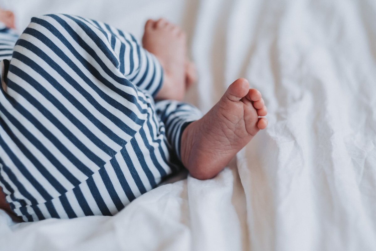 Tiny newborn foot laying on bed