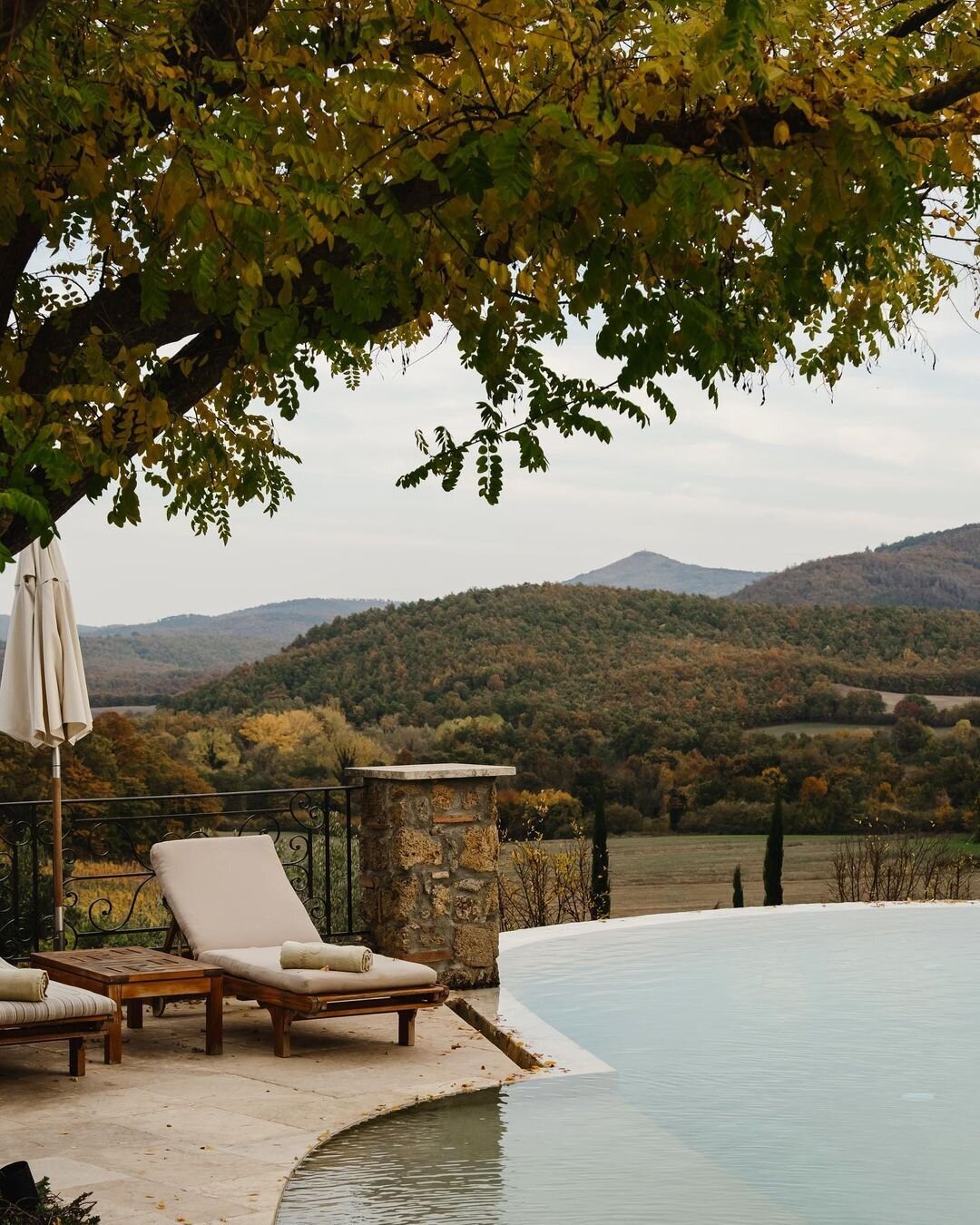 The infinity pool at Borgo Santo Pietro with white linen sun loungers and Tuscan countryside views
