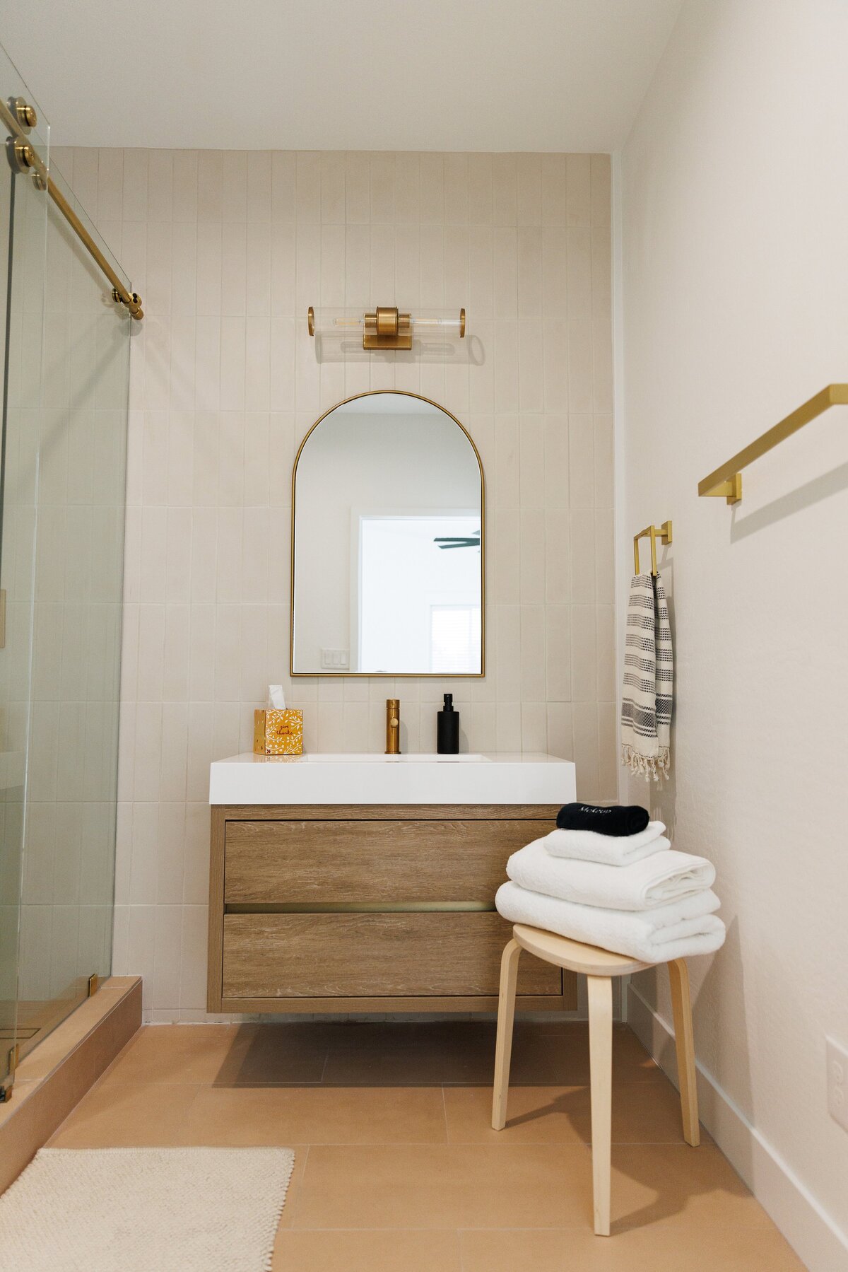 luxury bathroom with neutral vanity and gold curved mirror