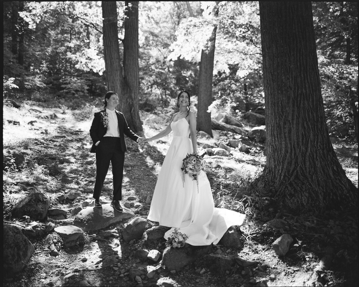 Medium format film wedding portrait of two brides holding hands in the woods in the Hudson Valley