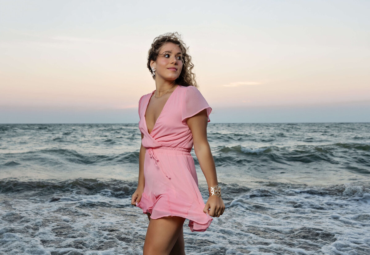 Senior portrait of a girl in a pink romper by the water at the Peninsula on Lake Erie