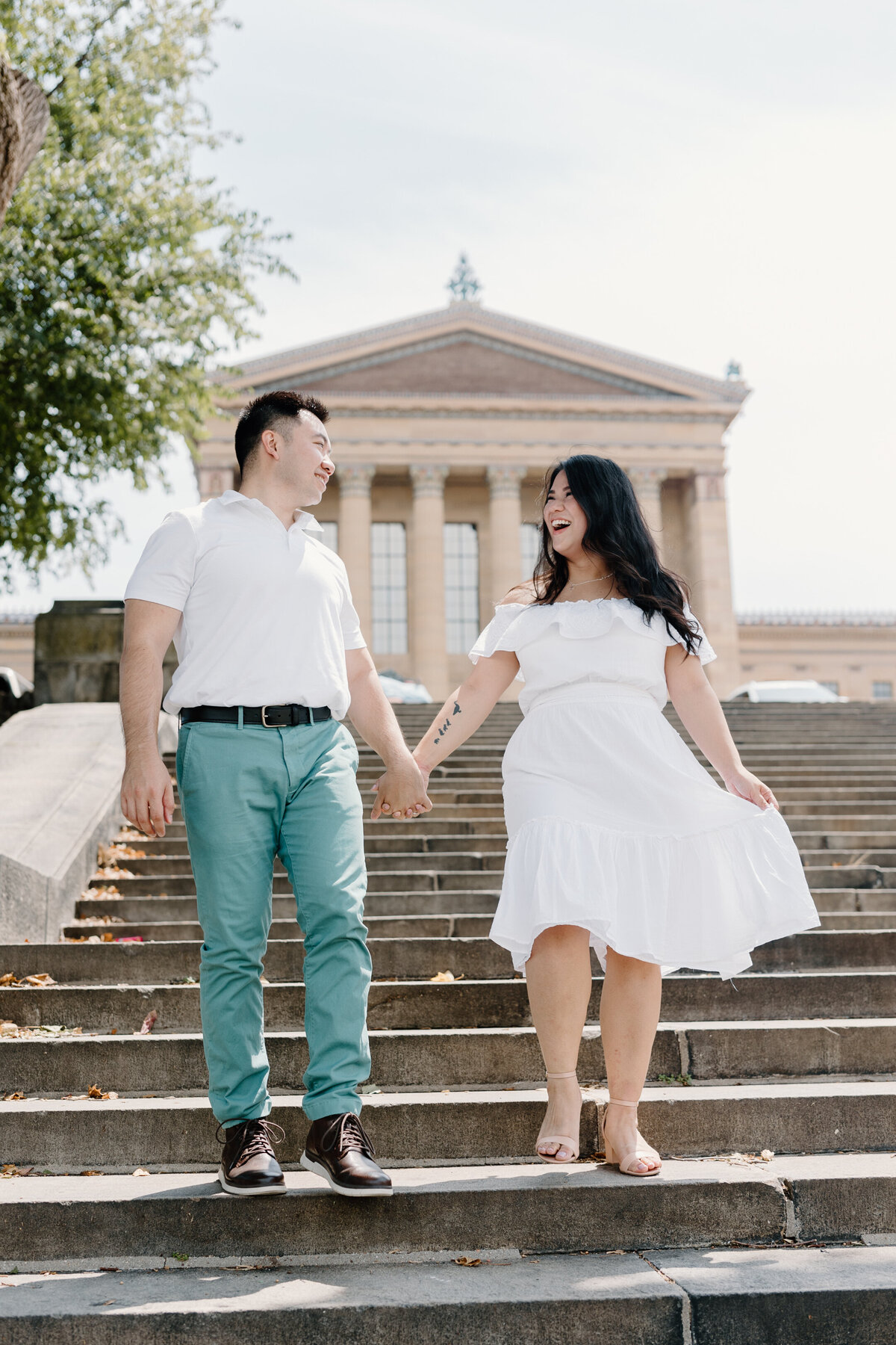 couple holding hands walking down steps at philadelphia art museum