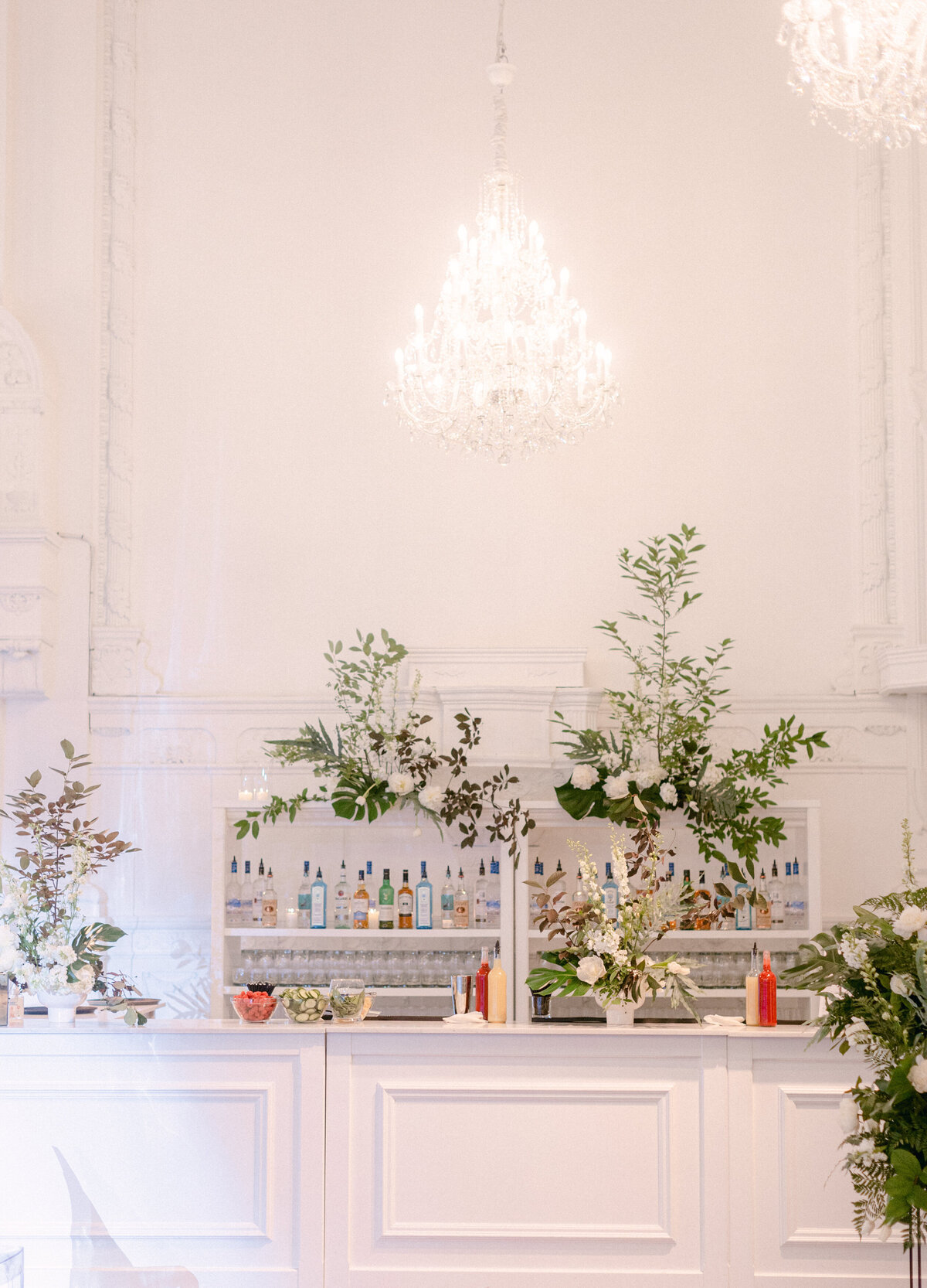 A wedding reception bar is decorated with textured organic greenery at Maison Principale.