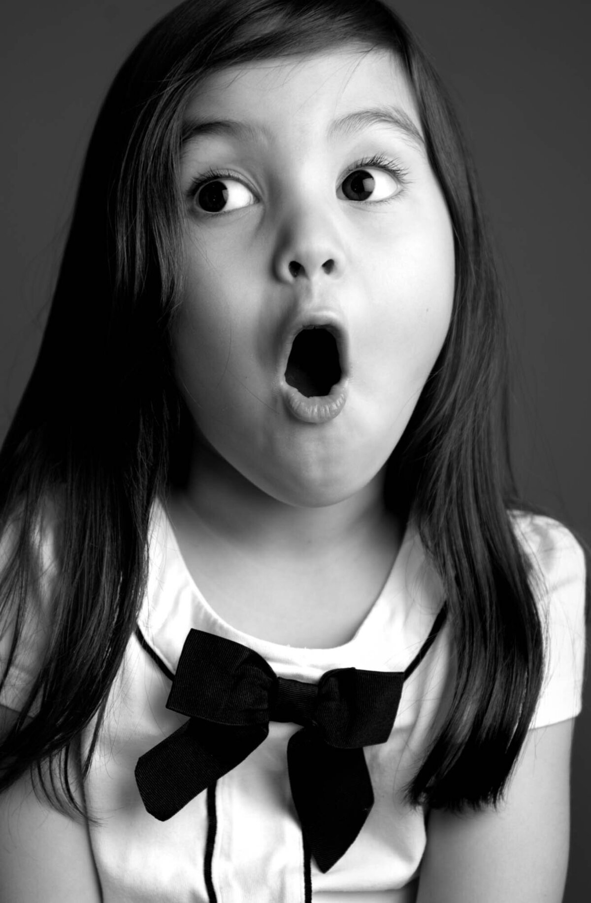 A cheerful little girl with a big smile and a colorful bow tie, radiating joy and playfulness.