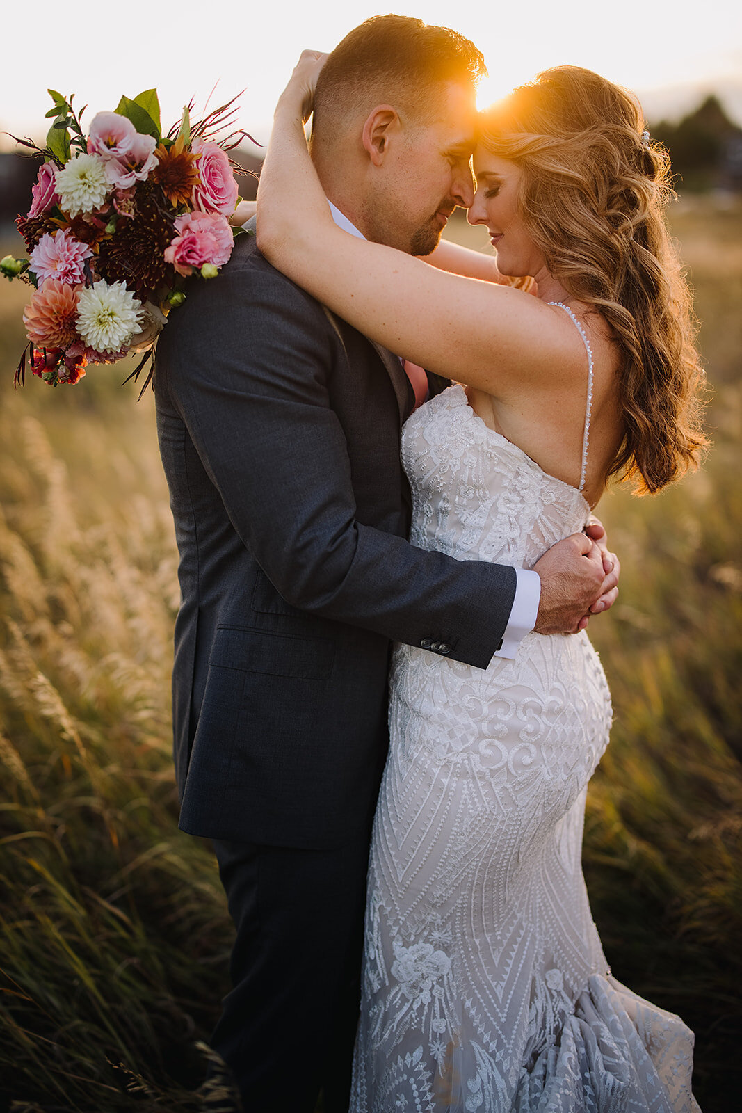 Bride and groom during their sunset photos with a pink and burgundy bouquet.