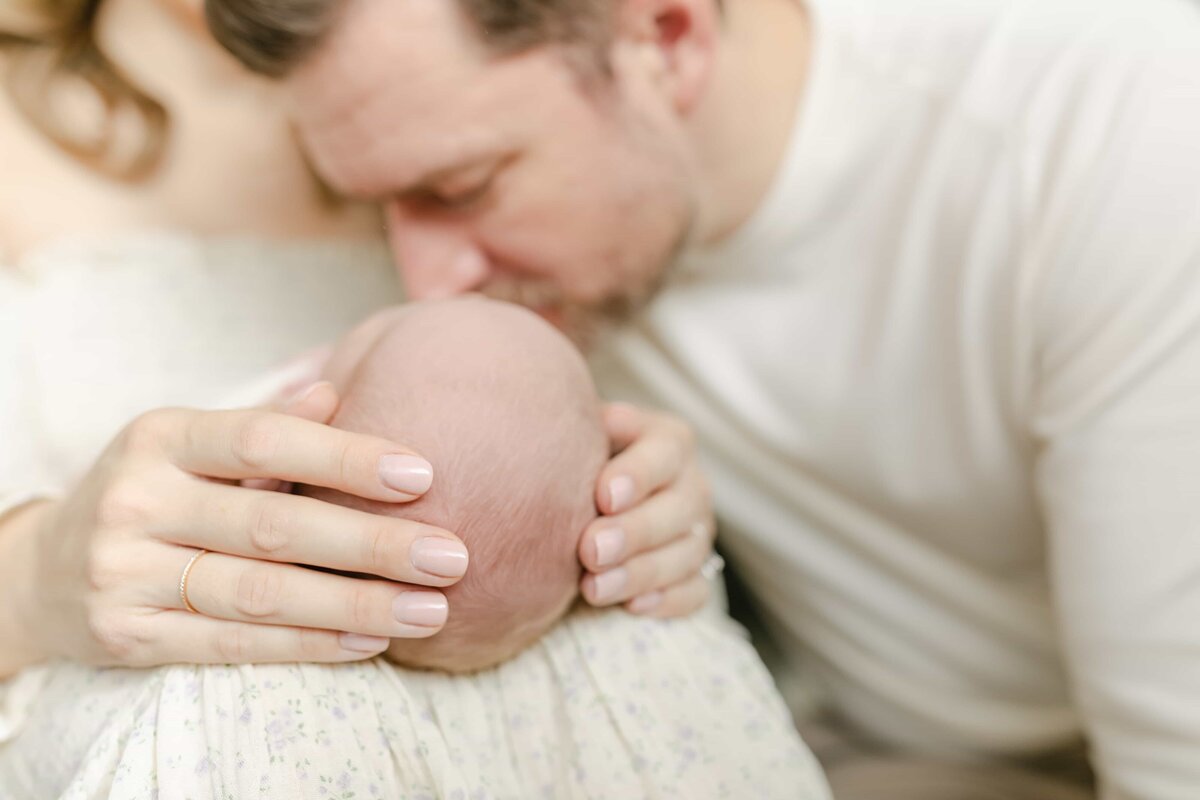 Orange County Newborn Photographer - father kissing the head of a newborn baby