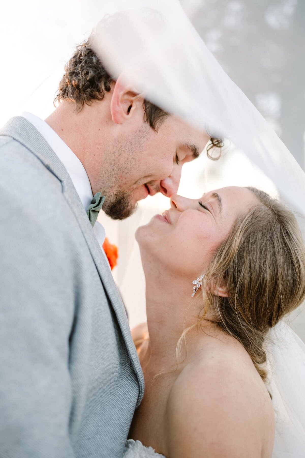 Groom and bride nuzzle nose under veil at farm wedding near Charlottesville VA