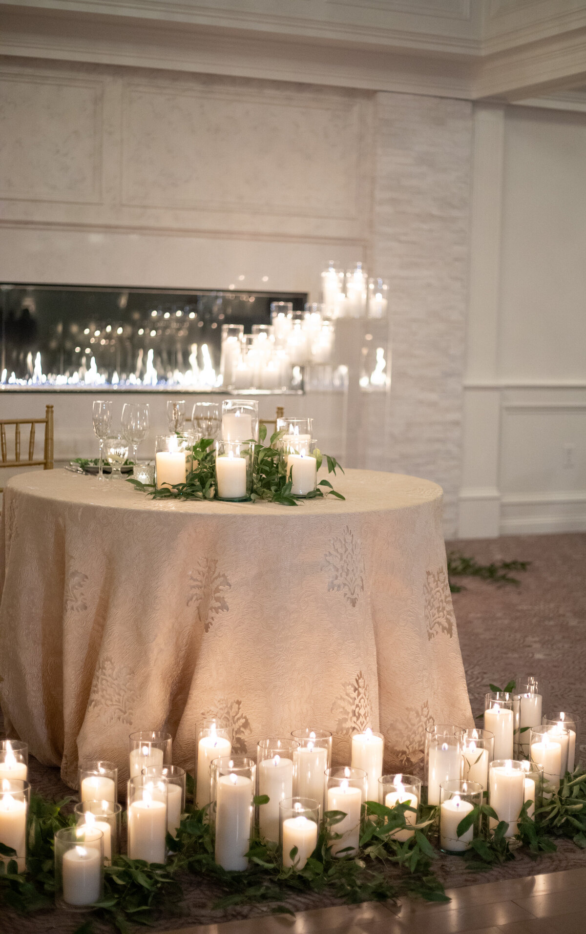 White candles and greenery surrounding bride and groom table