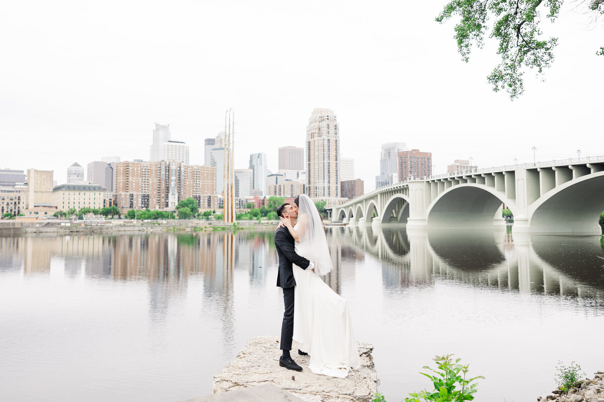 couple embracing in front of bridge taken by minneapolis wedding photographer