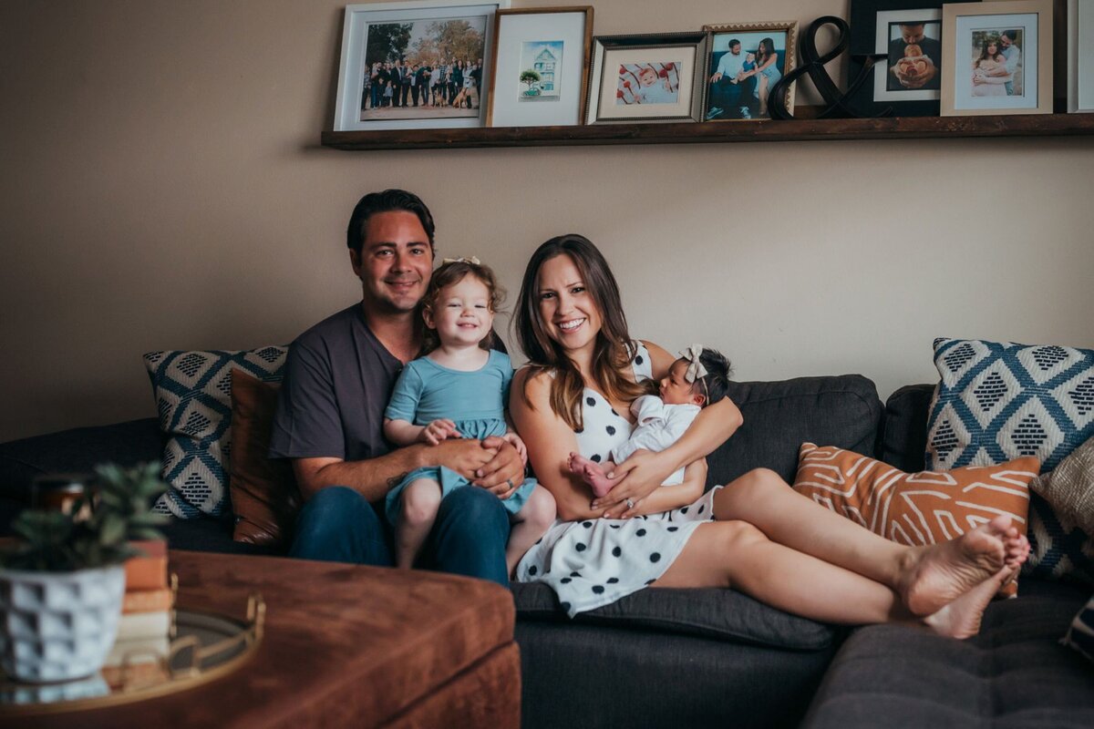newborn parents with toddler and newborn lifestyle in living room by Orange County photographer Francesca Marchese