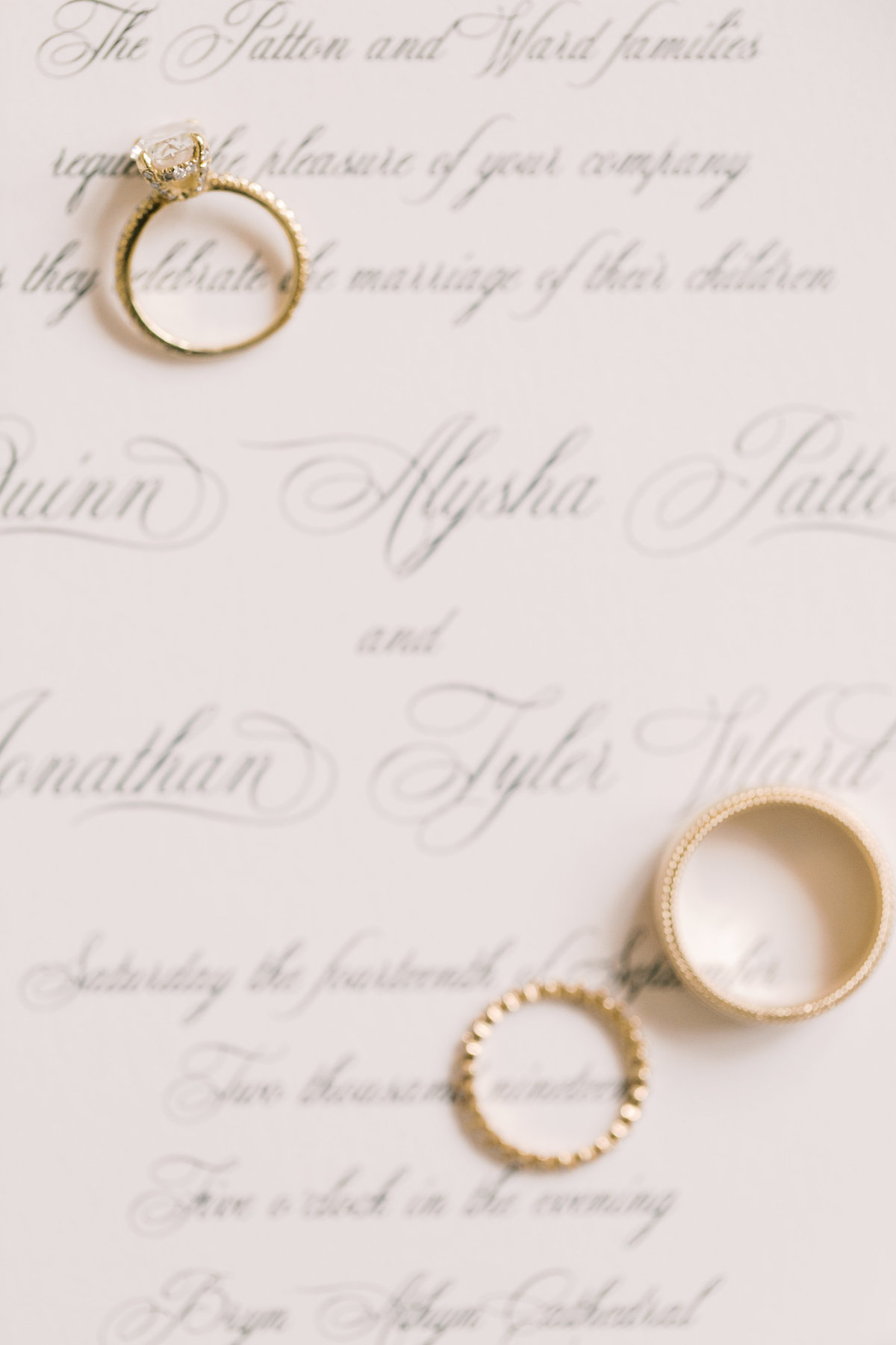 gold wedding bands sitting on wedding invitations during detail shots