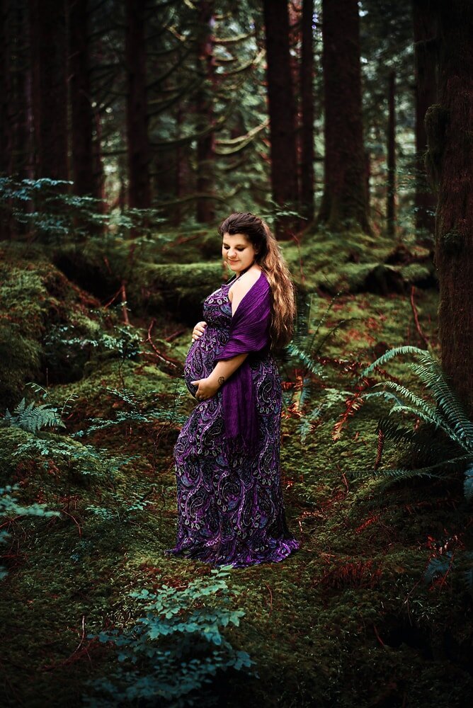 Pregnant woman in purple dress in the forest.