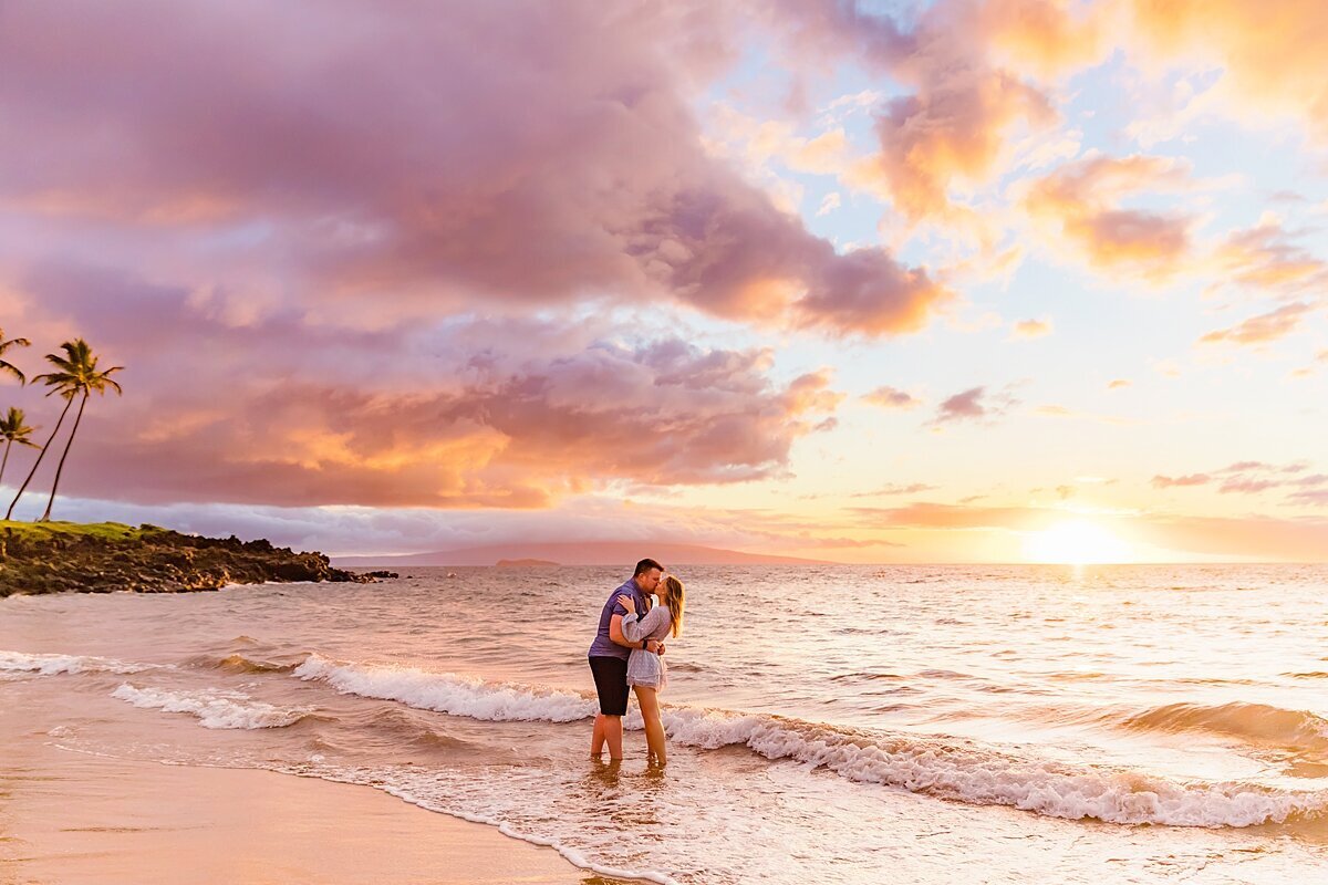 Sunset photo of a couple kissing on the beach with their feet in the water during their proposal photoshoot in Wailea