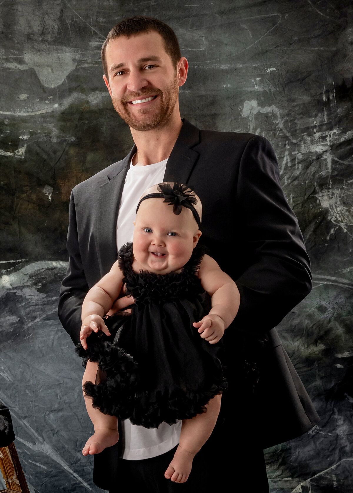 Dad holds his daughter in front of him while they both smile