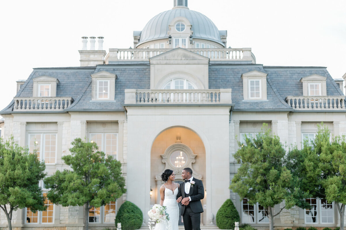 Luxury wedding portrait of a couple standing in front of a grand chateau-style estate